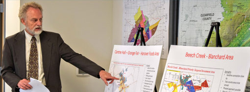 Secretary Don Kiel points at maps of Grange Fair and Beech Creek areas.